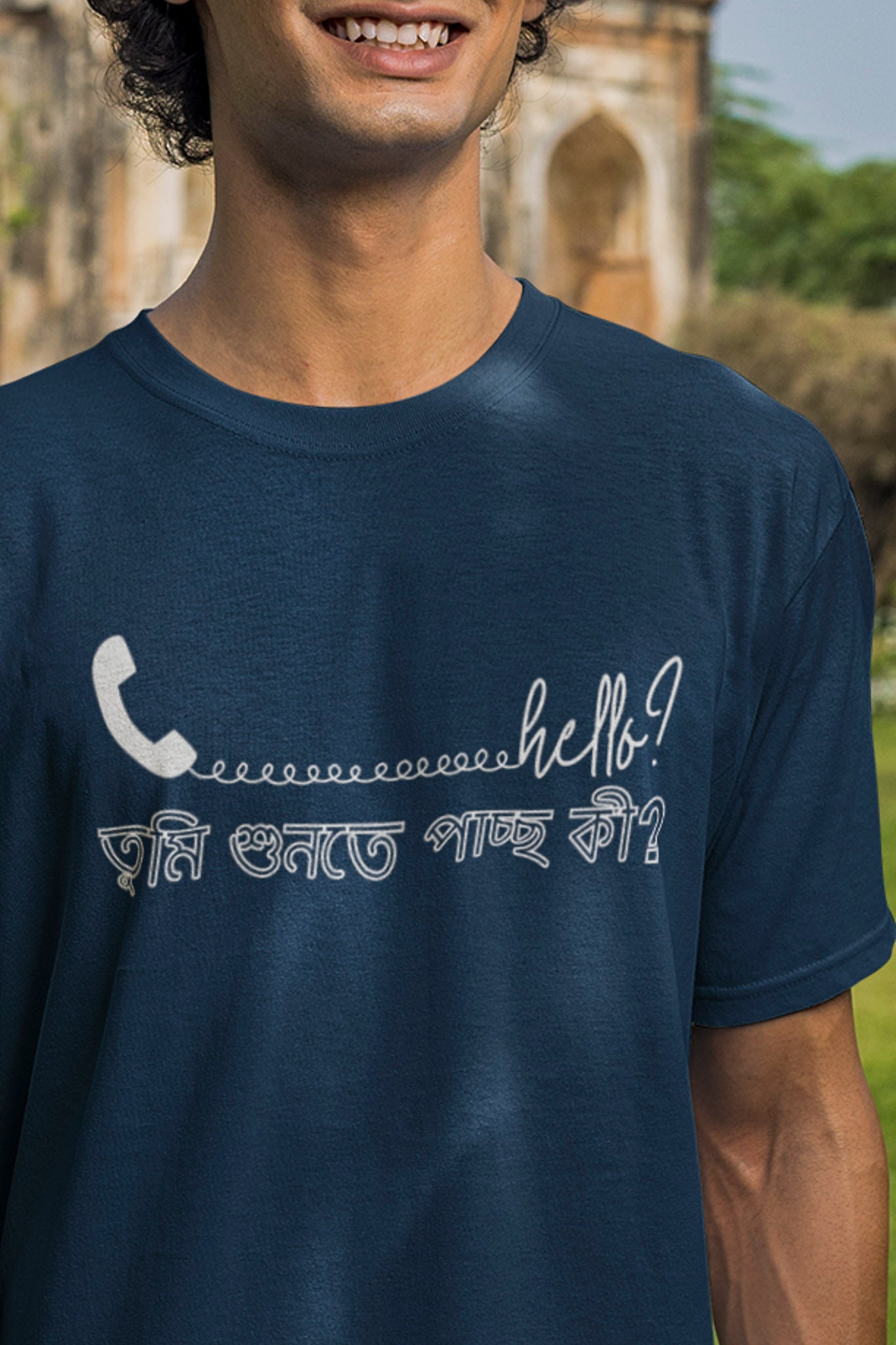 Person wearing a navy blue t-shirt with a white graphic and text outdoors.