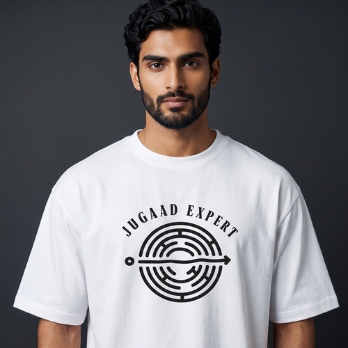 A man wearing a white crew-neck t-shirt with a black graphic print that reads 'JUGAAD EXPERT' around a circular maze design, set against a dark gray studio background.