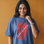 A woman wearing a blue graphic t-shirt with the text 'BOSS KAUN HAI?' in red and white, posing against a solid orange background.