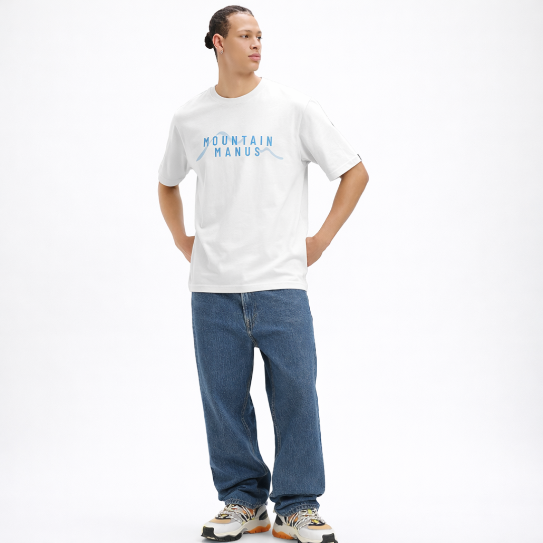 Person wearing a white t-shirt with 'Mountain Manus' text and blue jeans on a white background