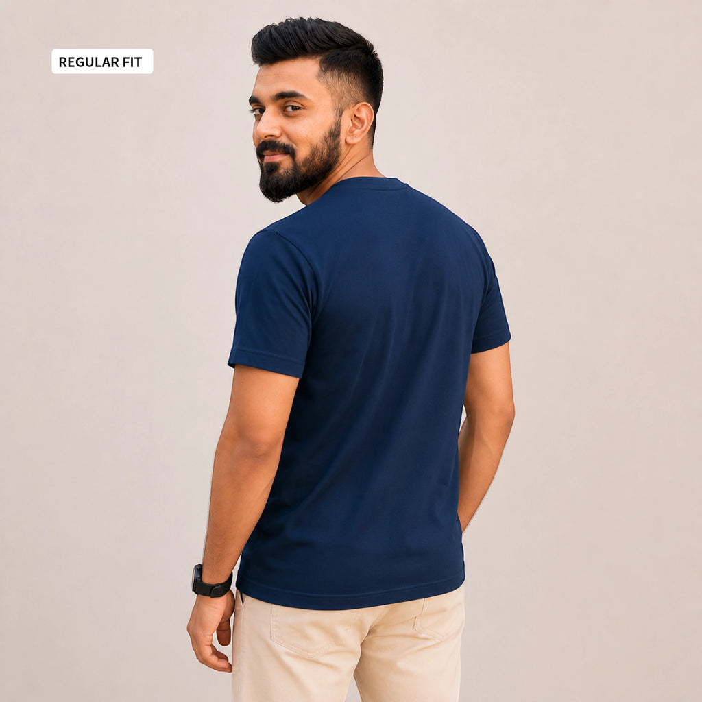A man wearing a navy blue short-sleeve t-shirt and beige pants, shown from the back and side against a plain beige background. A small label in the top-left corner reads 'REGULAR FIT'.