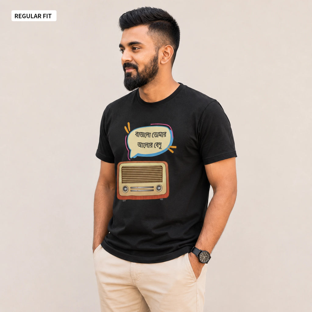 A man wearing a black short-sleeve t-shirt with a graphic print of a retro radio and Bengali text inside a speech bubble, paired with beige trousers, standing against a plain light beige background.