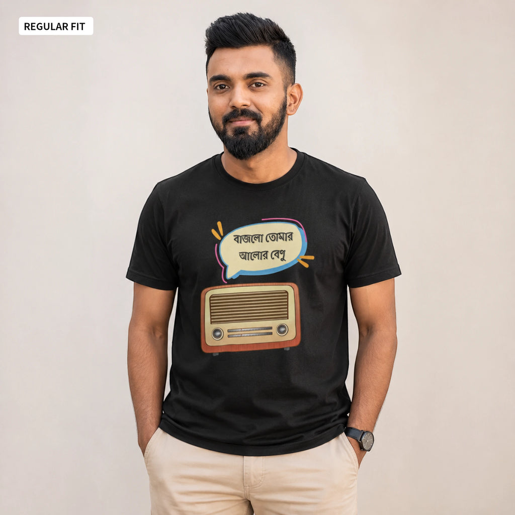 A man wearing a black graphic t-shirt with a retro radio and Bengali text design, paired with beige trousers, standing against a plain beige background.