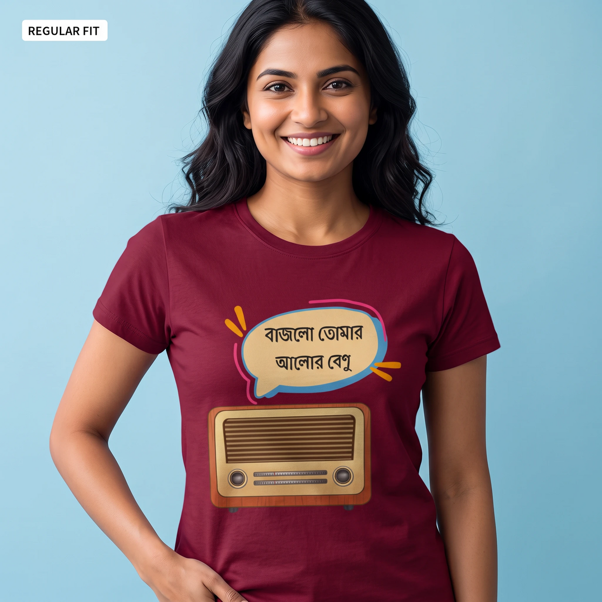 A woman wearing a maroon short-sleeve t-shirt with a graphic print of a retro radio and a speech bubble with Bengali text, set against a light blue background.