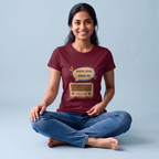 A woman sitting cross-legged on a light blue studio background wearing a maroon graphic t-shirt with a cartoon radio and Bengali text speech bubble, paired with blue jeans.