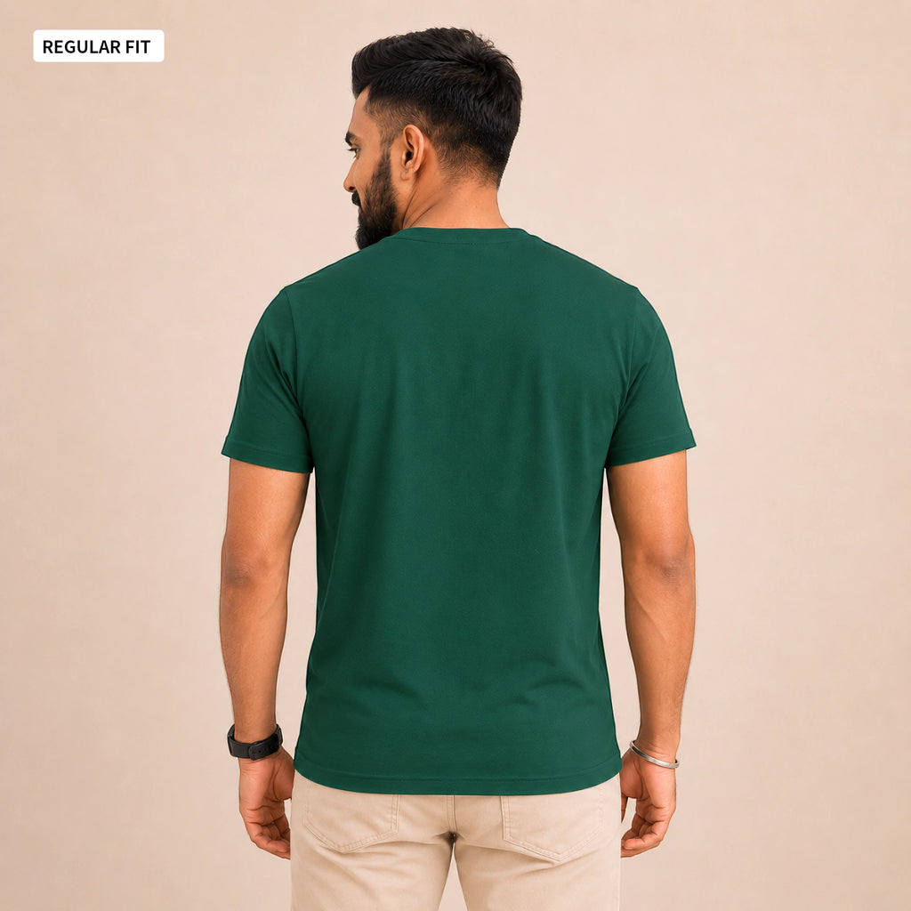 A man wearing a dark green short-sleeve t-shirt, viewed from the back, paired with beige trousers, against a solid beige background. A small label in the top-left corner reads 'REGULAR FIT'.