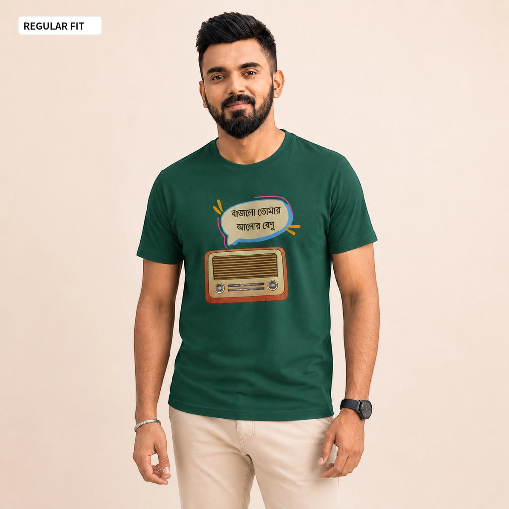 A man wearing a dark green short-sleeve t-shirt with a retro radio and speech bubble graphic in Bengali, paired with beige pants, standing against a solid beige background.