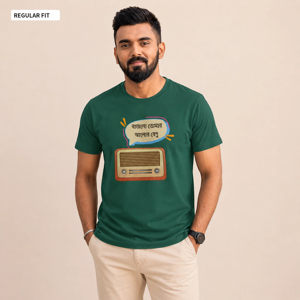 A man wearing a dark green graphic t-shirt with a retro radio and Bengali text design, paired with beige pants, standing against a solid beige background.