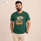 A man wearing a dark green graphic t-shirt with a retro radio and Bengali text design, paired with beige pants, standing against a solid beige background.