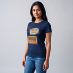 A woman modeling a navy blue short-sleeve t-shirt with a graphic print of a vintage radio and Bengali text inside a speech bubble, paired with blue jeans against a light gray studio background.
