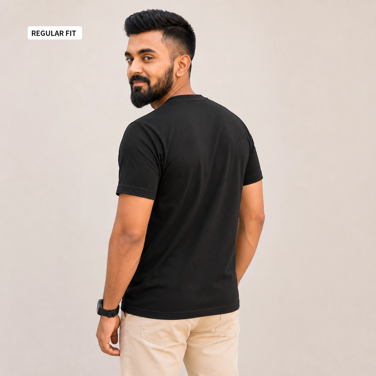 A man wearing a black short-sleeve t-shirt and beige pants, shown from the back and side against a plain light gray background. A small label in the top-left corner reads 'REGULAR FIT'.