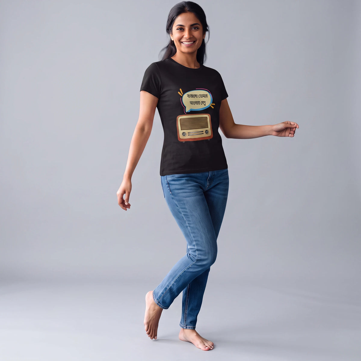 A woman modeling a black short-sleeve graphic t-shirt with a retro radio and speech bubble design, paired with blue jeans, against a solid gray studio background.