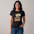 A woman wearing a black graphic t-shirt with a cartoon radio and Bengali text print, paired with blue jeans, standing against a plain light gray background.