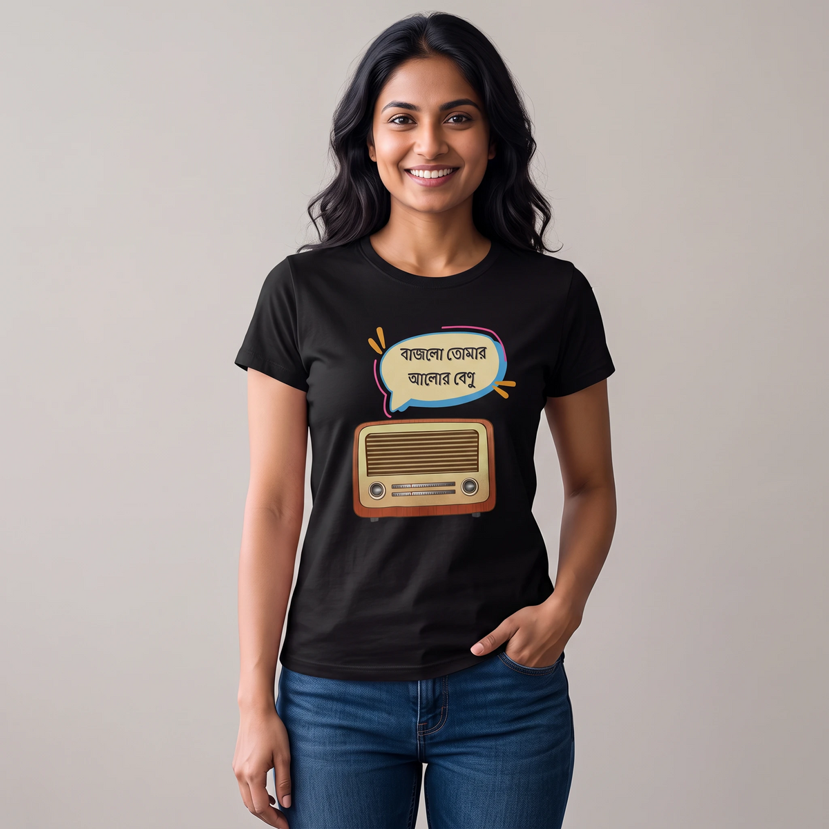 A woman wearing a black graphic t-shirt with a cartoon radio and Bengali text print, paired with blue jeans, standing against a plain light gray background.