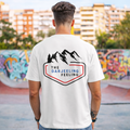 Person wearing a white t-shirt with 'The Darjeeling Feeling' logo in an urban setting.
