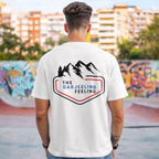 Person wearing a white t-shirt with 'The Darjeeling Feeling' logo in an urban setting.