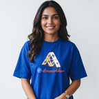A smiling woman with long dark hair wearing a royal blue t-shirt with a graphic of a geometric triangle and the text 'atmanirbhar' on the front, set against a plain light gray background.