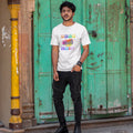 Person wearing a white t-shirt with colorful text in front of a green door.