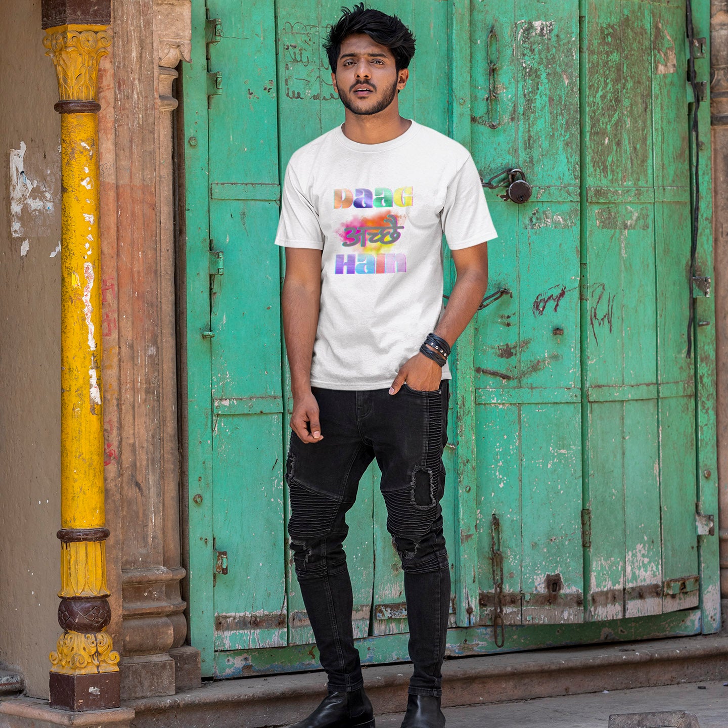 Person wearing a white t-shirt with colorful text in front of a green door.
