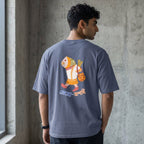 A man wearing a slate blue-gray t-shirt with a colorful cartoon fish graphic on the back, standing in front of a concrete wall.