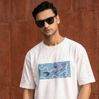 A man wearing a white crewneck t-shirt with a graphic print of a koi fish swimming in blue waves, set against a textured reddish-brown wall.