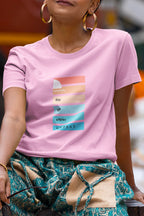 Person wearing a pink t-shirt with a graphic design, sitting outdoors.