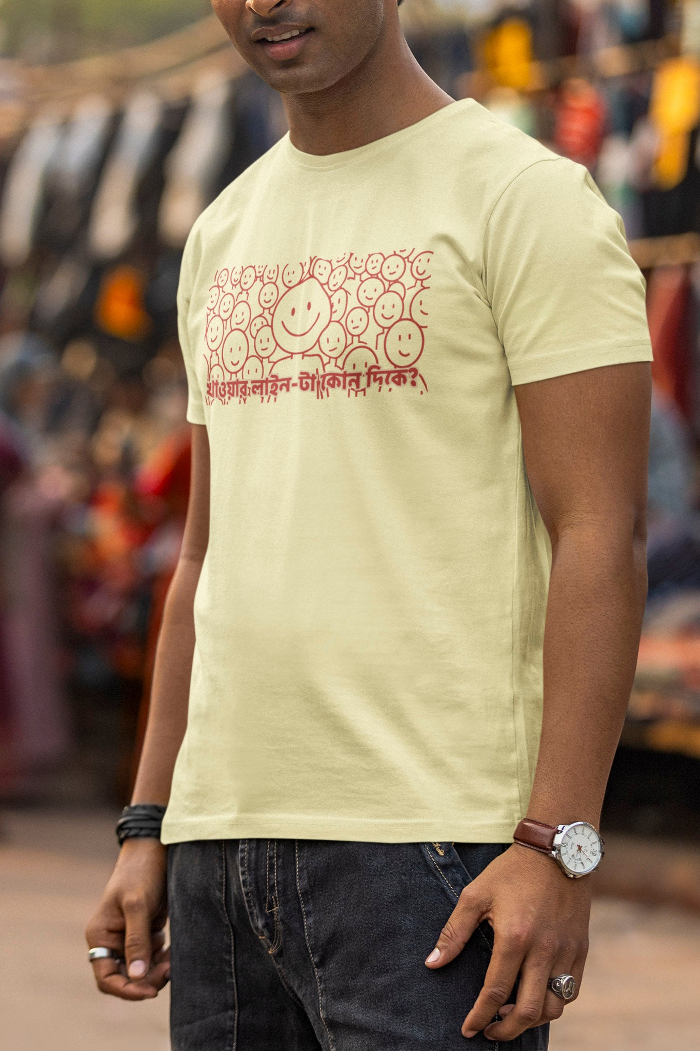 Man wearing a light-colored t-shirt with text and graphics, standing outdoors.