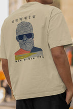 Beige t-shirt with a graphic of a man with sunglasses on the back, worn by a person.